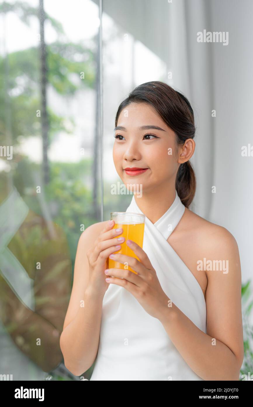 Hermosa mujer de belleza asiática linda chica se siente feliz bebiendo jugo de naranja para una buena salud por la mañana Foto de stock