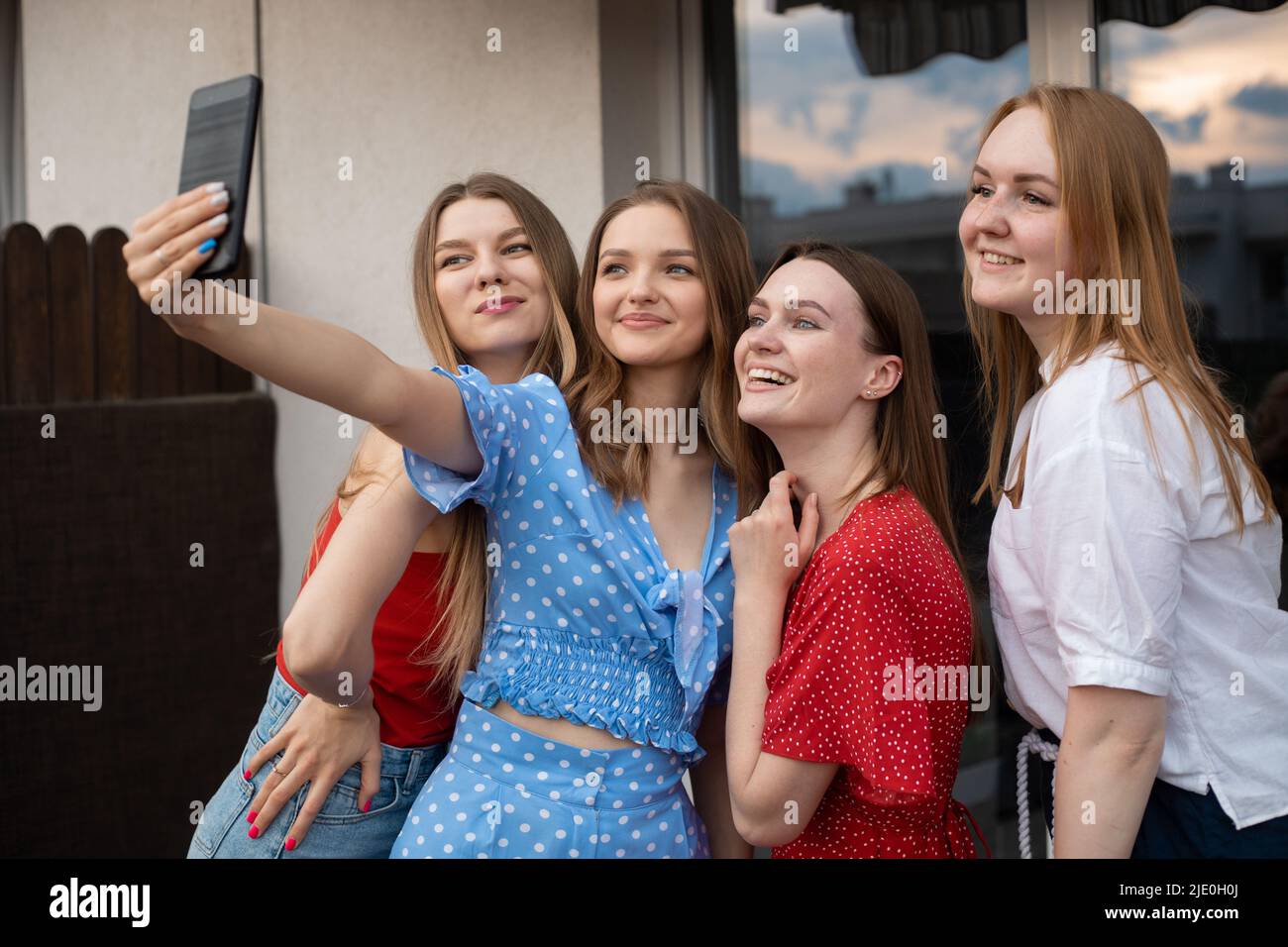 Mujeres jóvenes felices de pie juntas en la terraza, sonriendo y tomando selfie en primer plano smartphone. Divertirse y disfrutar de la recreación al aire libre. Chicas Foto de stock