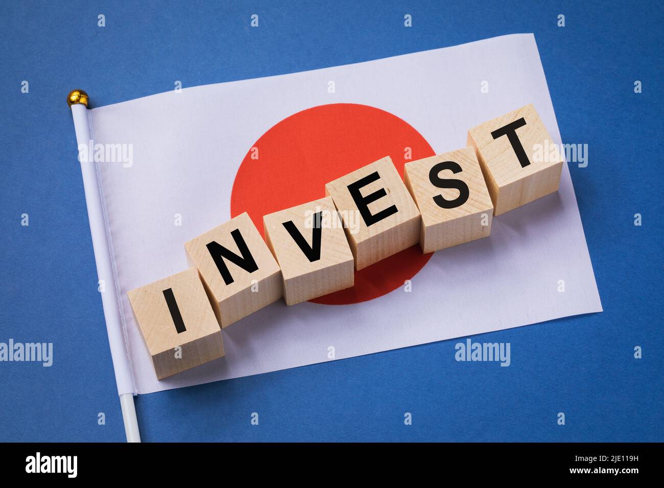 Cubos de madera con texto y bandera sobre fondo coloreado, concepto de inversión de Japón Foto de stock