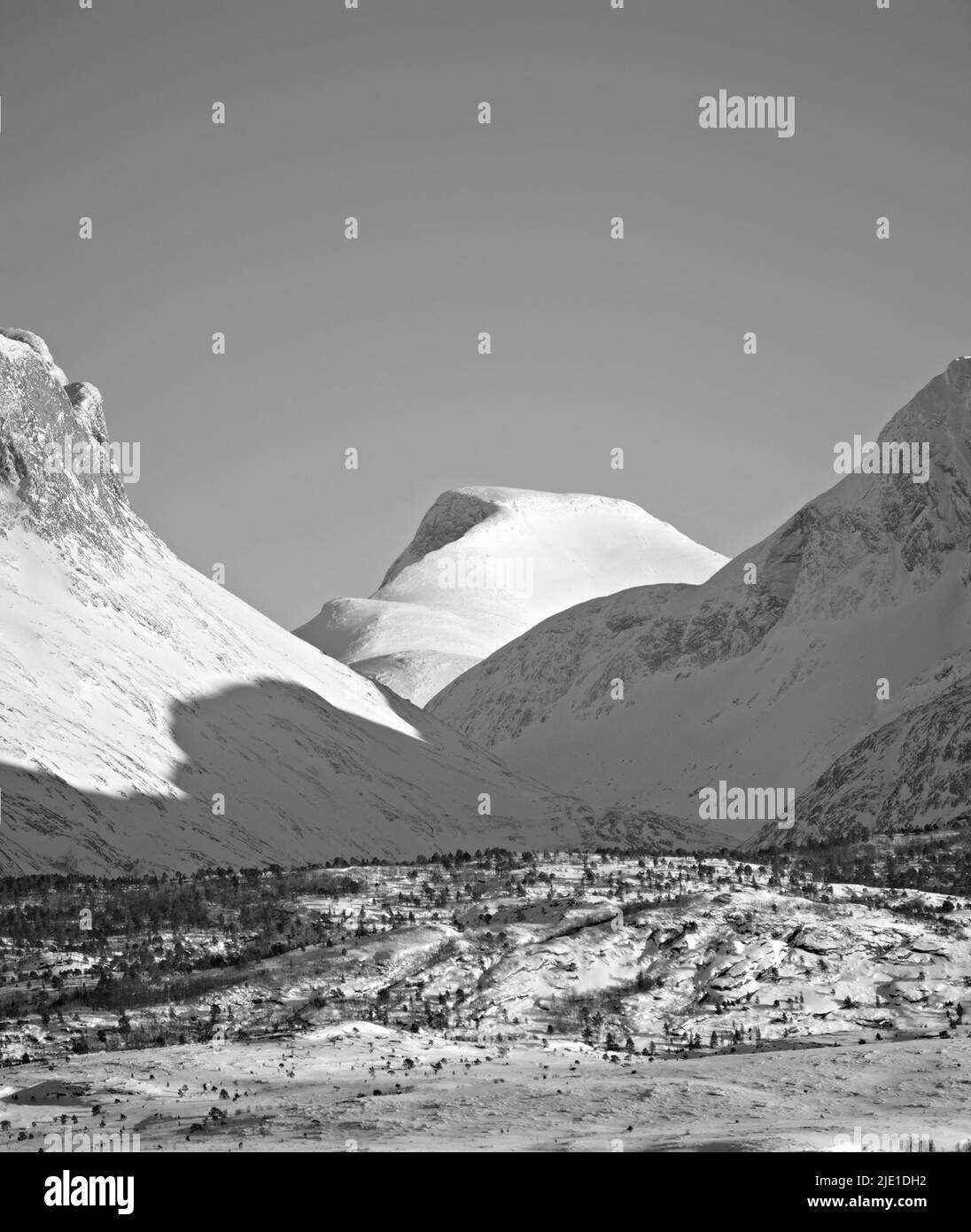 Vista de las montañas nevadas y del glaciar al norte del Círculo Polar Ártico en blanco y negro. Colinas abiertas y vacías contra el cielo despejado Foto de stock