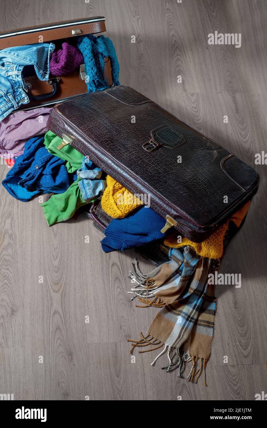 Las maletas rebosan con ropa en suelo. Armario de clasificación y textiles. Vida sostenible Fotografía de stock -