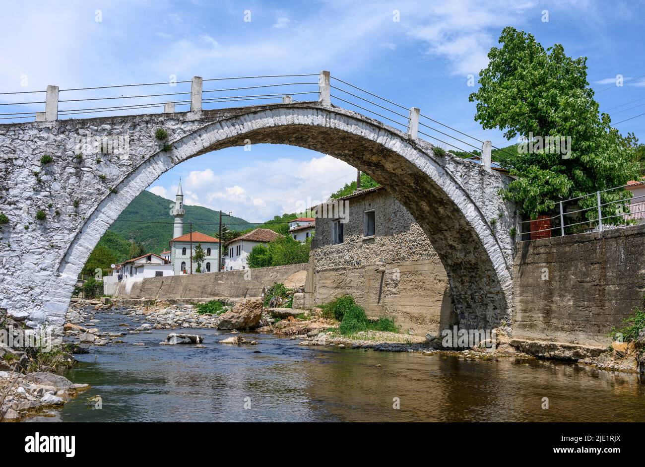 El pueblo Pomak de Medousa visto a través del arco de su antiguo puente de piedra, Thermes Comunity, Región de Xanthi, Tracia Occidental, Grecia. El pueblo Pomak Foto de stock