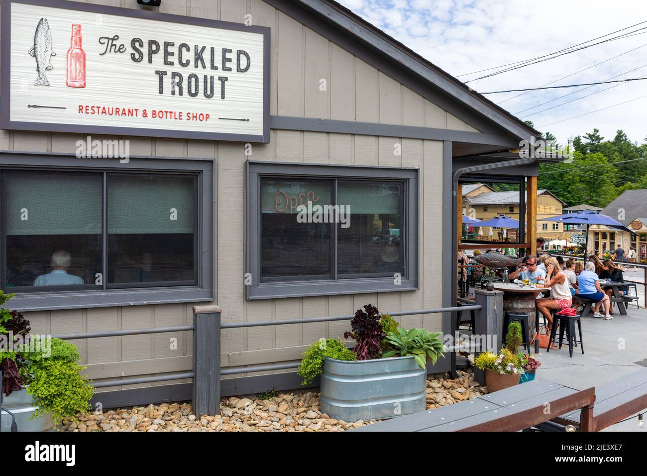 BLOWING ROCK, NC, EE.UU.-20 DE JUNIO de 2022: El restaurante Speckled Trout y tienda de botellas, con comedor al aire libre. Edificio, señalización y clientes. Foto de stock