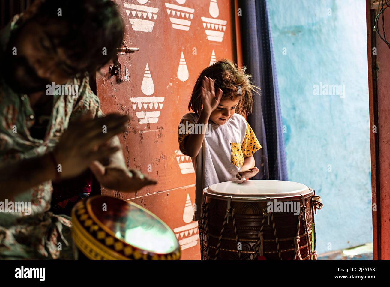 Hombre adulto medio tocando el tambor con su hija en casa Foto de stock