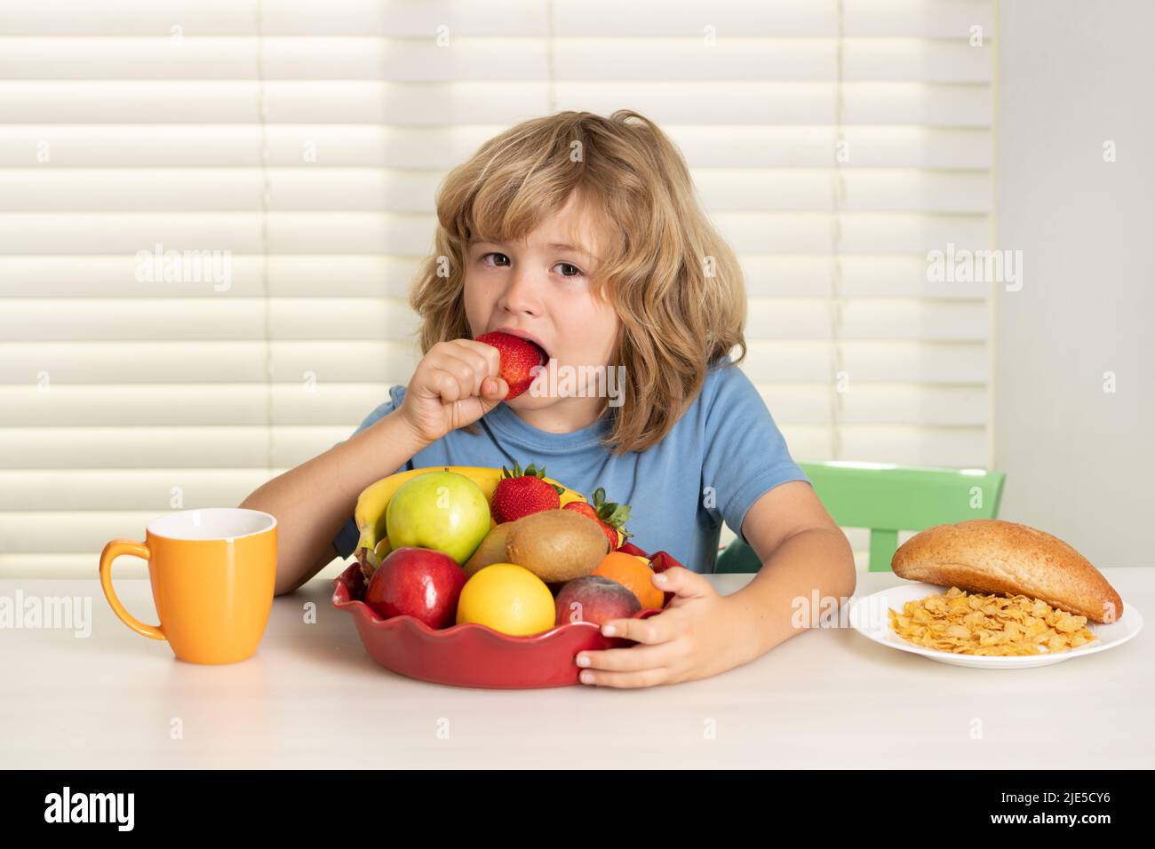 El niño come fresas, frutas orgánicas. Niño bot comer comida. Nutrición