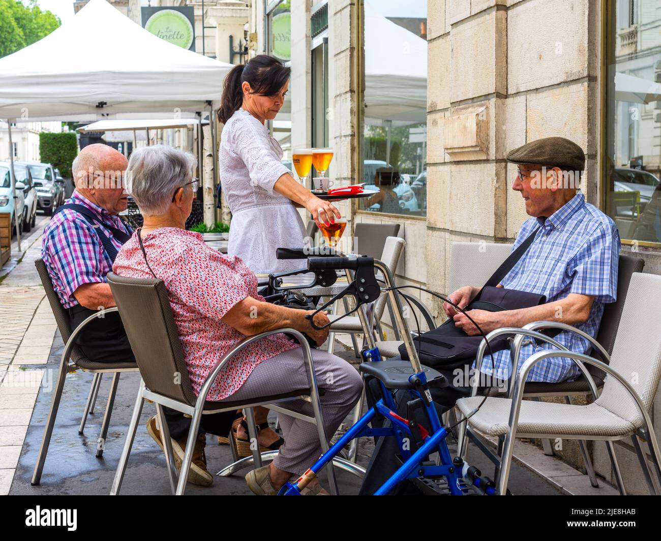 Tres ancianos sentados en la terraza del bar siendo servidos con bebidas - Tours, Francia. Foto de stock