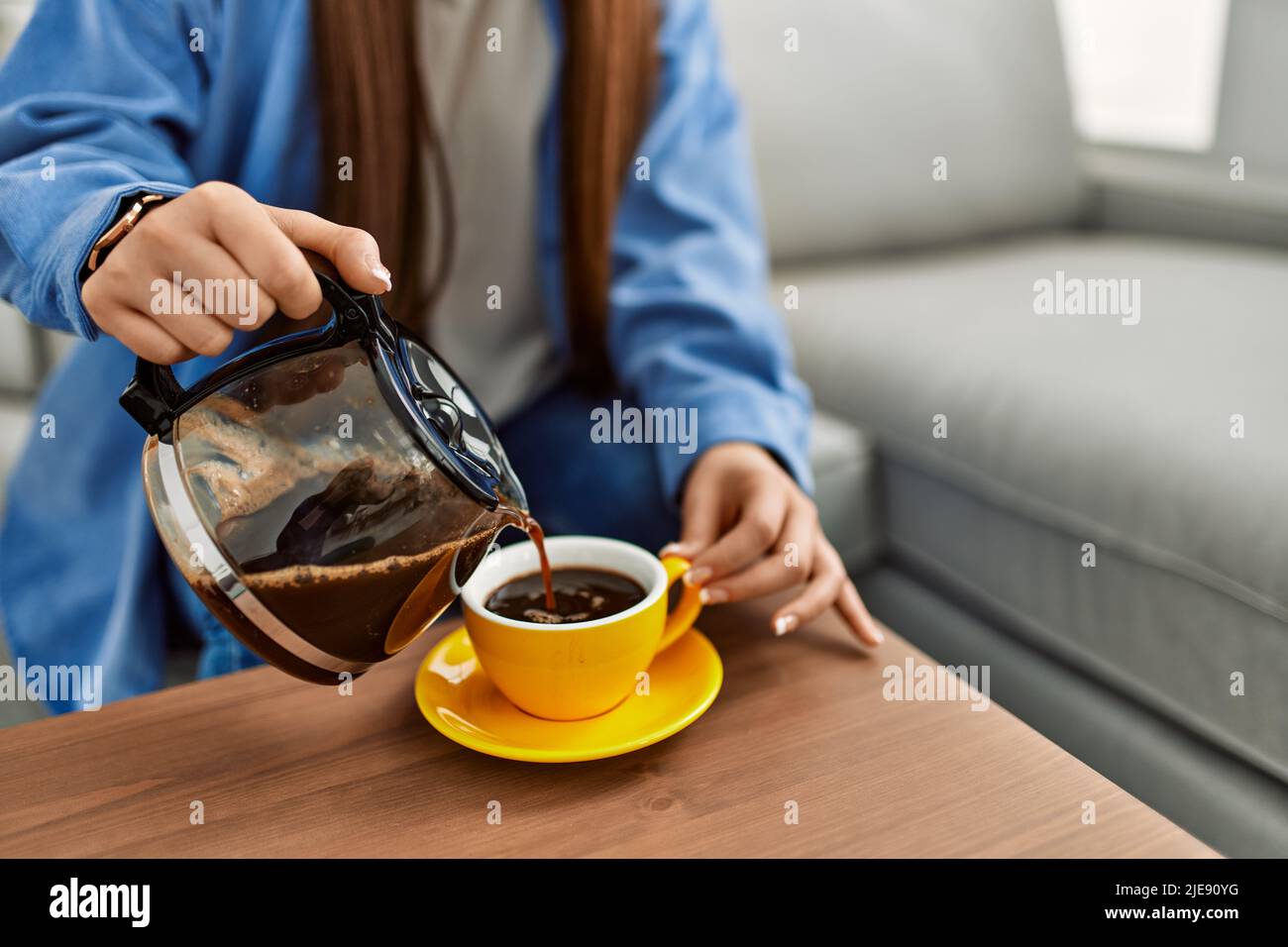 Chica tomando café sentado en el sofá de la casa Fotografía de stock - Alamy