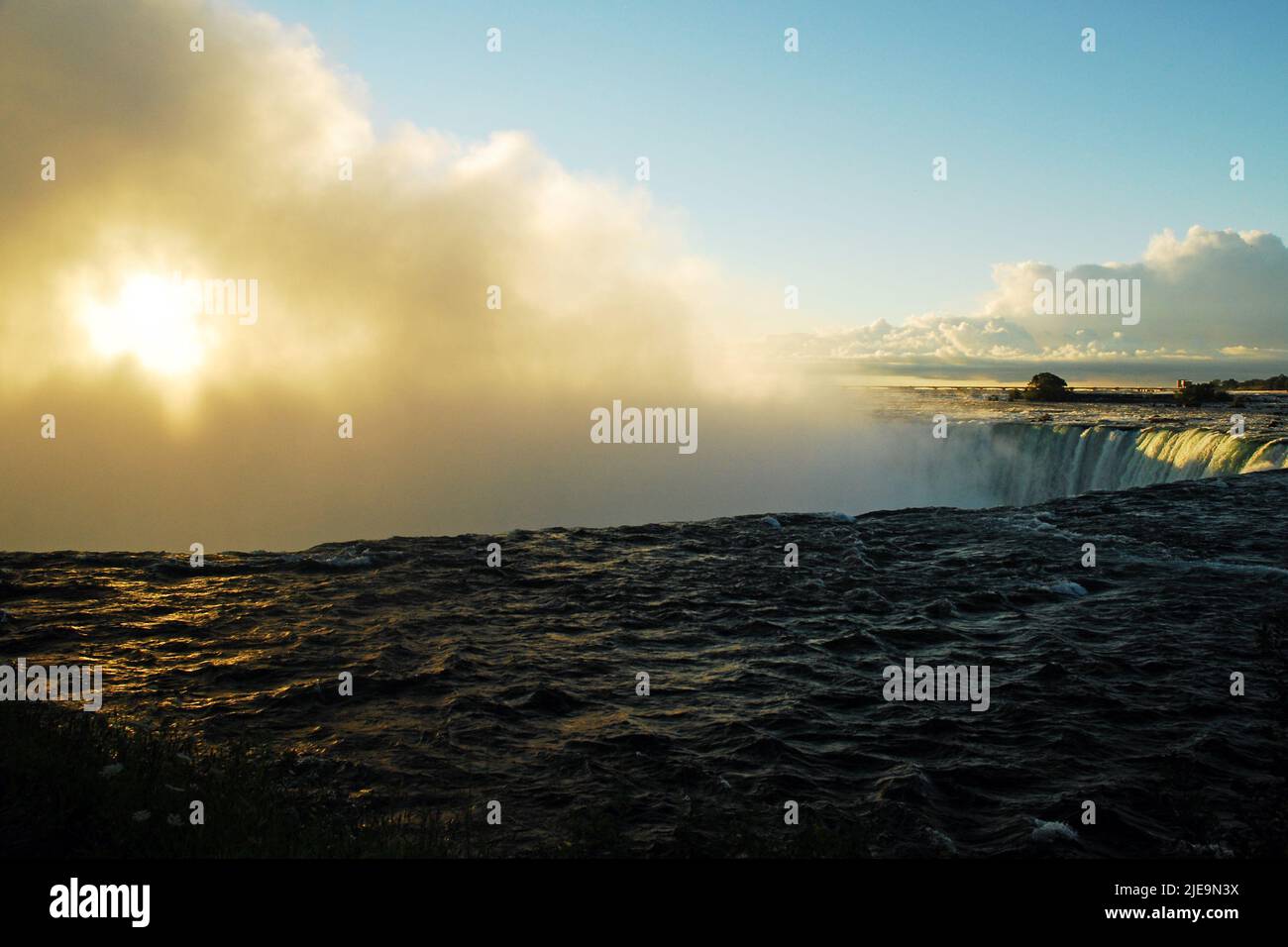 El sol brilla a través de la niebla y el agua pulverizada de Canadian Falls, o Horseshoe Falls, del Niágara en la madrugada del lado de Canadá Foto de stock