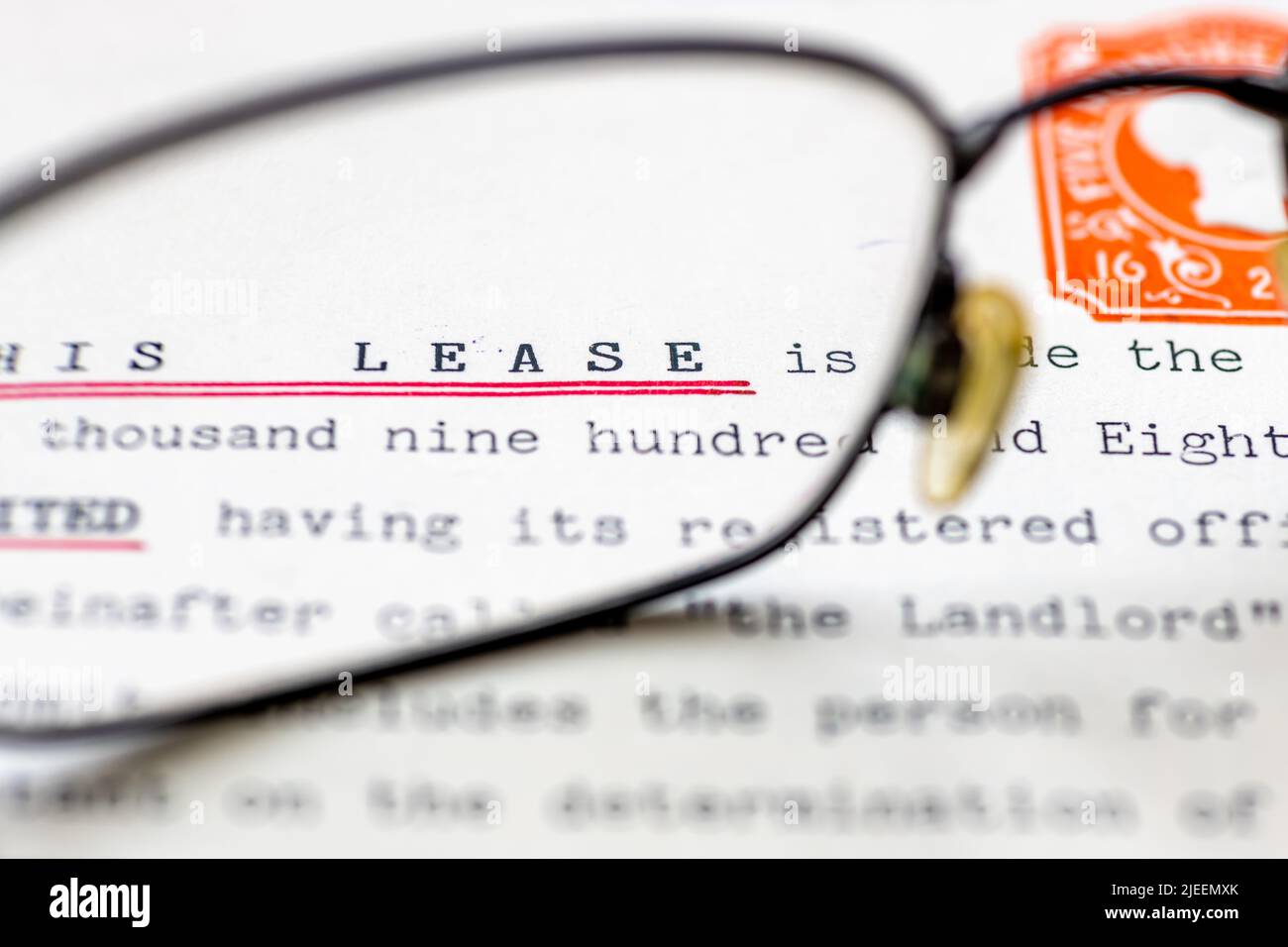 Primer plano de un contrato de arrendamiento para una propiedad que se muestra con gafas. Un documento legal para el alquiler a largo plazo o la propiedad de un local comercial o casa. Foto de stock