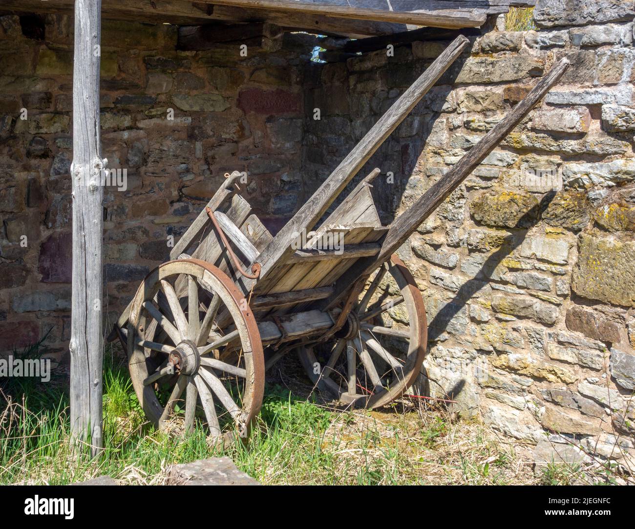 Carro medieval de madera en una pared de piedra en un ambiente soleado Foto de stock