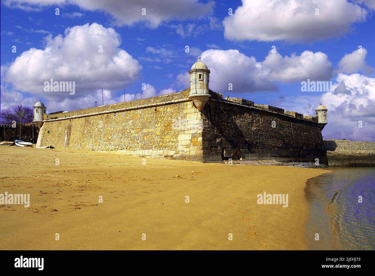 Arena dorada en la playa de Lagos, con las antiguas defensas del puerto, el siglo 17th Forte Bandeira, bajo un cielo azul profundo, Algarve, Portugal Foto de stock