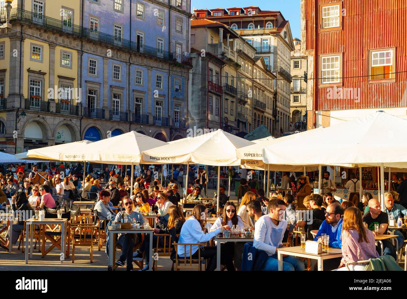 PORTO, PORTUGAL - 7 DE NOVIEMBRE de 2021: Gente sentada en cafés y restaurantes callejeros en el terraplén central, concurrida zona turística, arquitecto tradicional Foto de stock