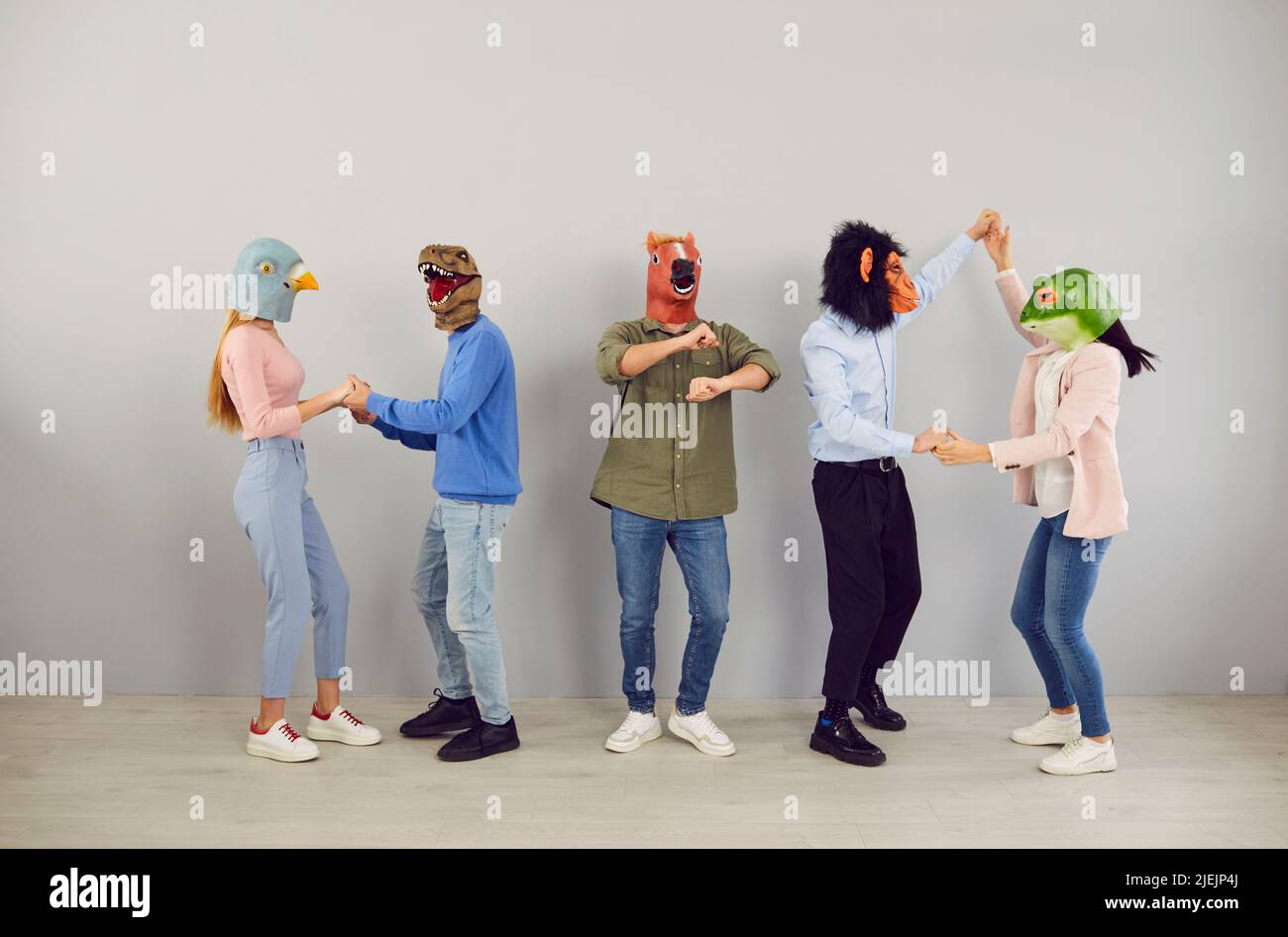 Gente divertida en máscaras de animales bailando juntos Foto de stock