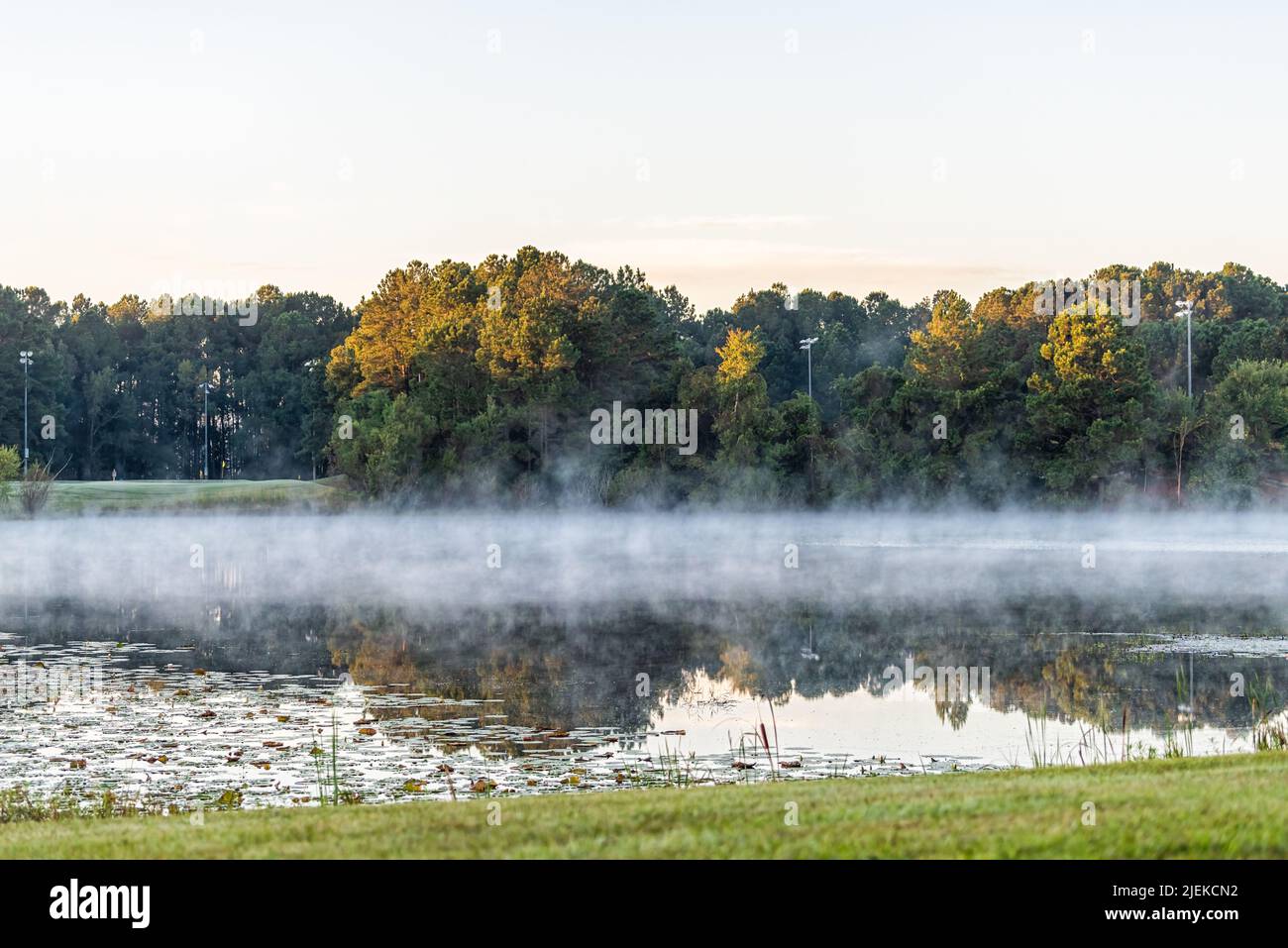 Pooler, ciudad de Georgia cerca de Savannah con salida del sol por la mañana vista del paisaje en un lago estanque con niebla creciente de vapor de agua en la noche fría y. Foto de stock