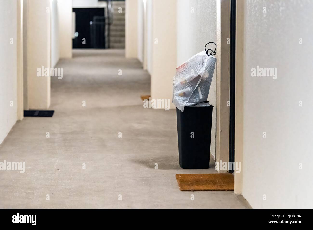Conserje puerta a puerta, servicio de recogida de basura para el apartamento con basura en papelera y bolsas de plástico para recoger en el pasillo del edificio residencial Foto de stock