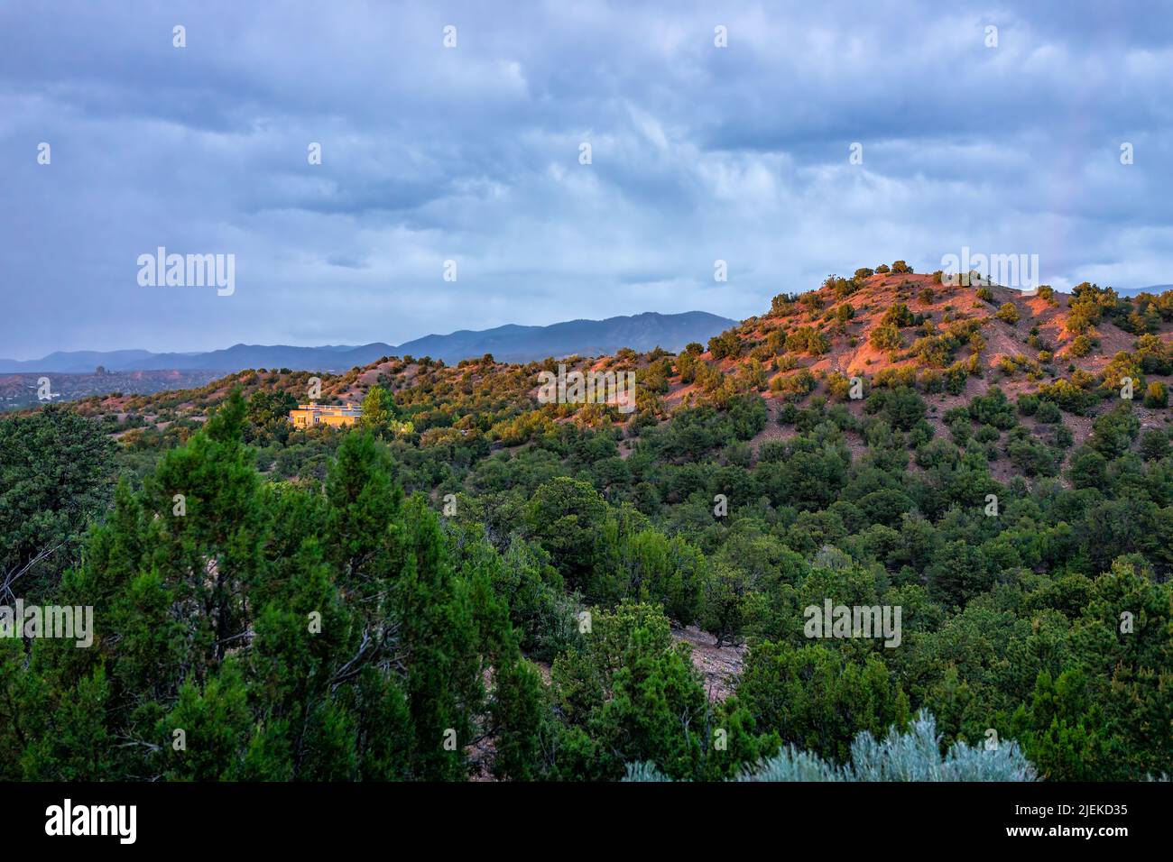 Puesta de sol en Santa Fe, montañas de Nuevo México en el barrio de la comunidad de Tesuque con luz solar en las casas, plantas verdes y cielo azul oscuro en el desierto alto Foto de stock