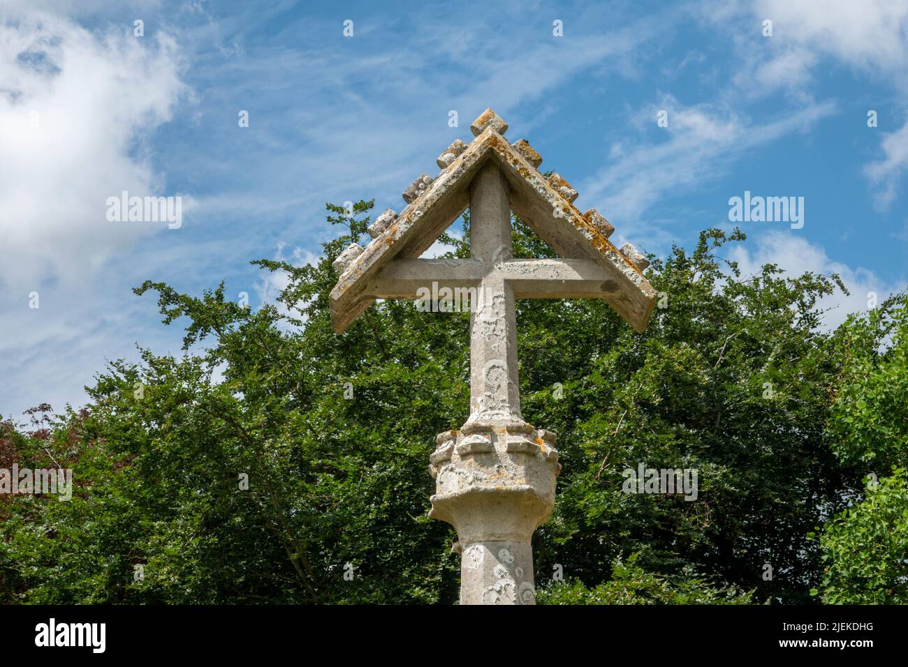 Cruz techada sobre un fondo de árbol verde en el cementerio de la Iglesia de San Miguel, Tunstall, Suffolk, Reino Unido Foto de stock