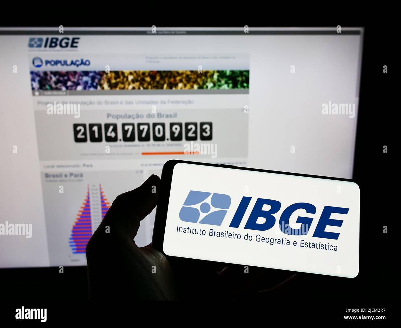 Persona que sostiene un smartphone con el logo del Instituto Brasileiro de Geografia e Estatitica (IBGE) en la pantalla con el sitio web. Enfoque la pantalla del teléfono. Foto de stock