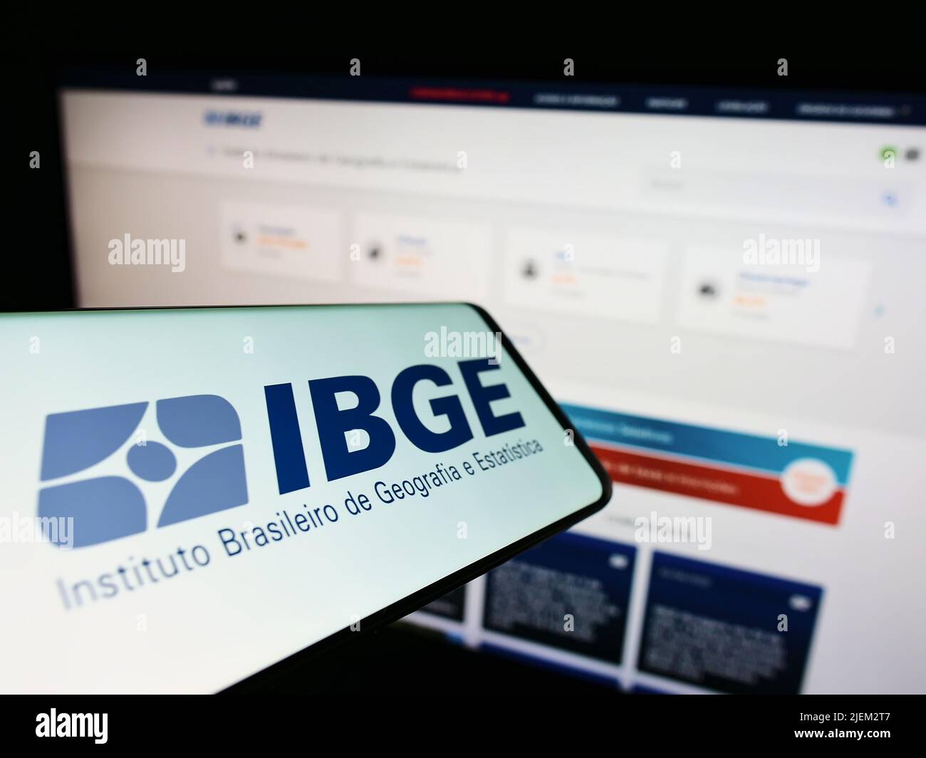 Celular con logo del Instituto Brasileiro de Geografia e Estatitica (IBGE) en pantalla con sitio web. Enfoque en la parte central derecha de la pantalla del teléfono. Foto de stock