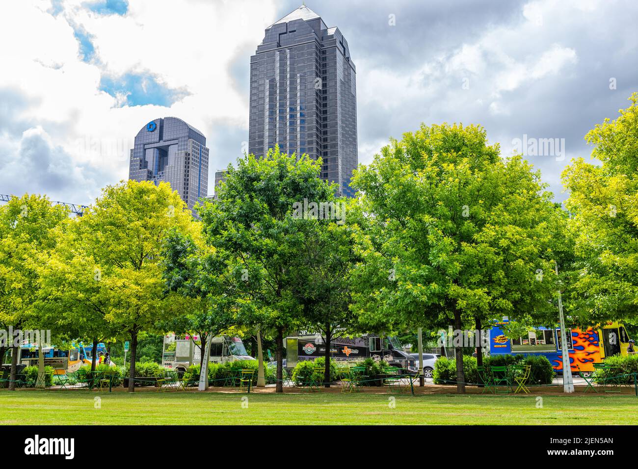 Dallas, EE.UU. - 7 de junio de 2019: Centro de Klyde Warren parque en verano con césped, árboles, camiones de alimentos y edificios torres paisaje urbano en día nublado en D. Foto de stock