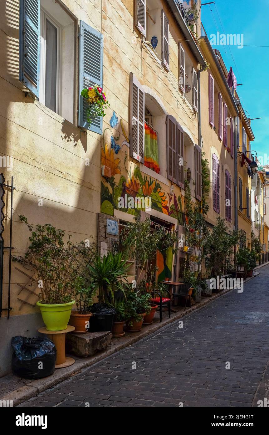 Marsella, Francia, 2022 de mayo, vista de una calle pavimentada estrecha con plantas y un mural en el distrito de Le Panier Foto de stock
