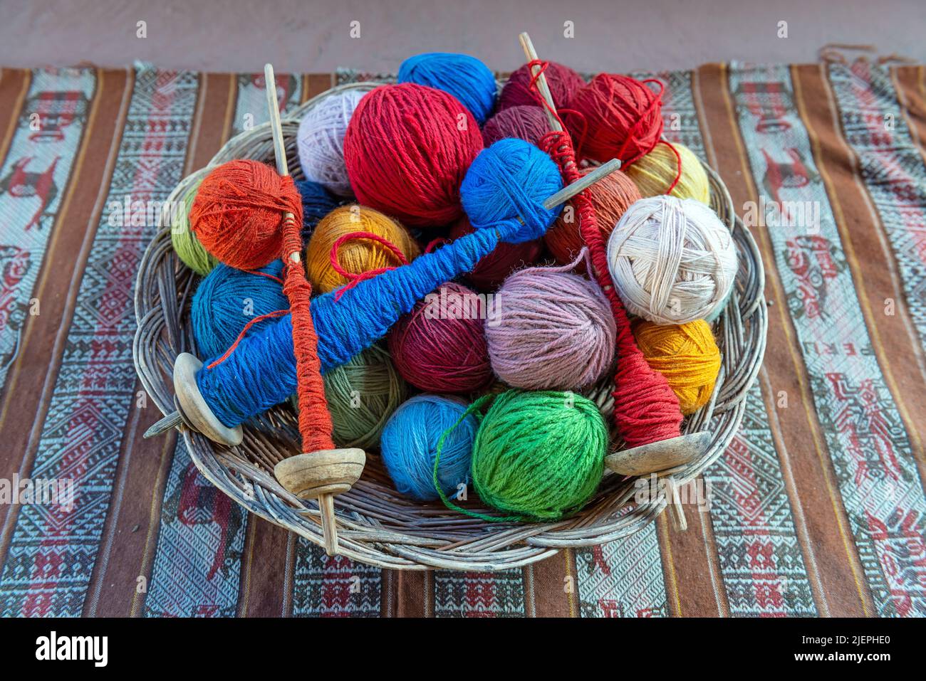 Vista superior de una cesta con bolas de lana de alpaca y husos hilados en un centro de producción textil en Cusco, Perú. Foto de stock
