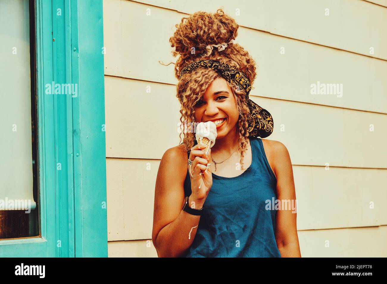 joven mujer adulto afro pelo sonriendo comer helado al aire libre verano disparo Foto de stock