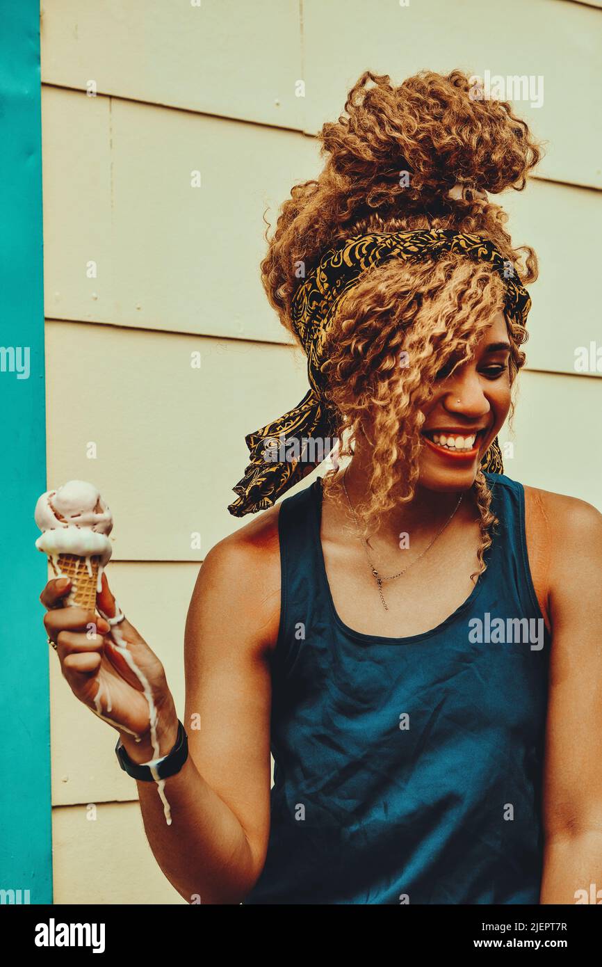 joven mujer adulto afro pelo sonriendo comer helado al aire libre verano disparo Foto de stock
