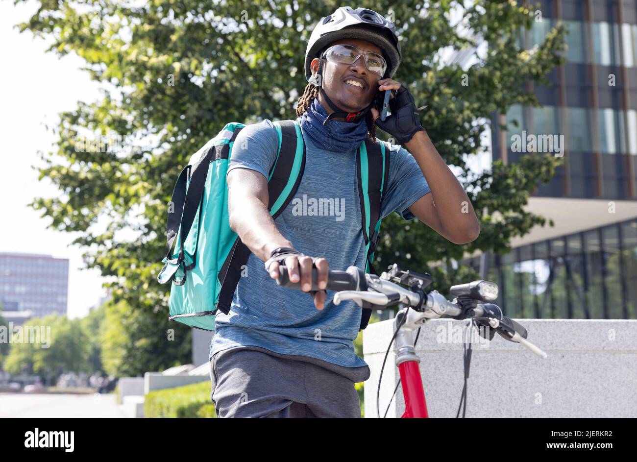 Mensajero en bicicleta Entrega de comida en la ciudad Takeaway haciendo llamadas en el teléfono móvil Foto de stock