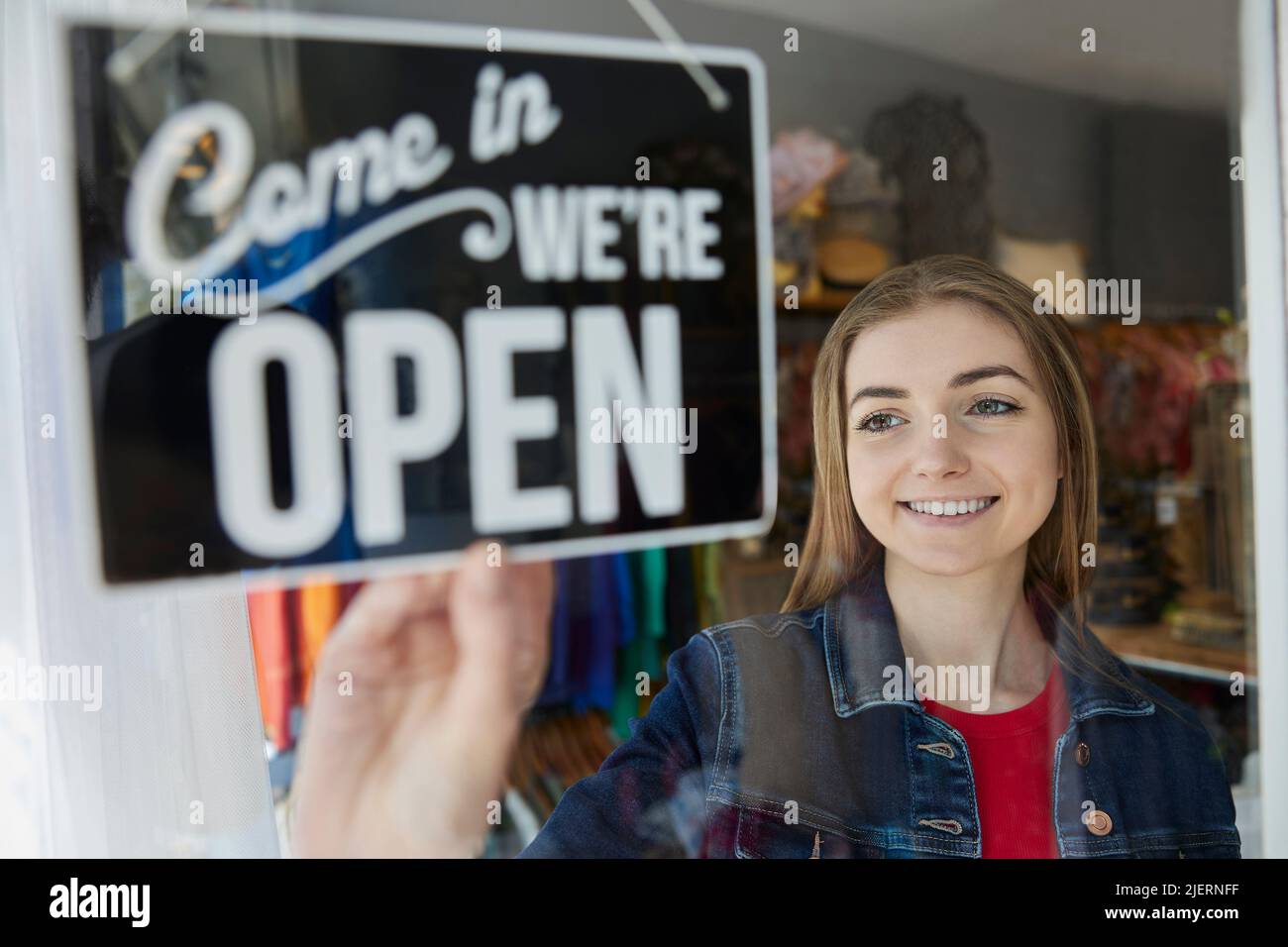 Sonriendo Mujer Dueño de la Pequeña Empresa Turning Round Open Sign in Shop Window Foto de stock