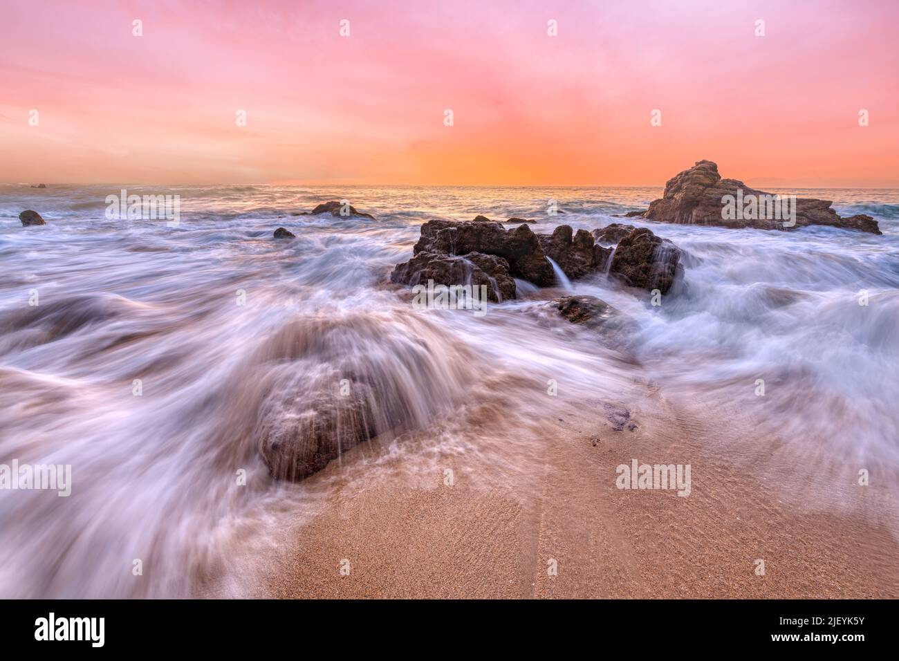 El agua fluye a través de las rocas del océano en la resolución alta del amanecer Foto de stock
