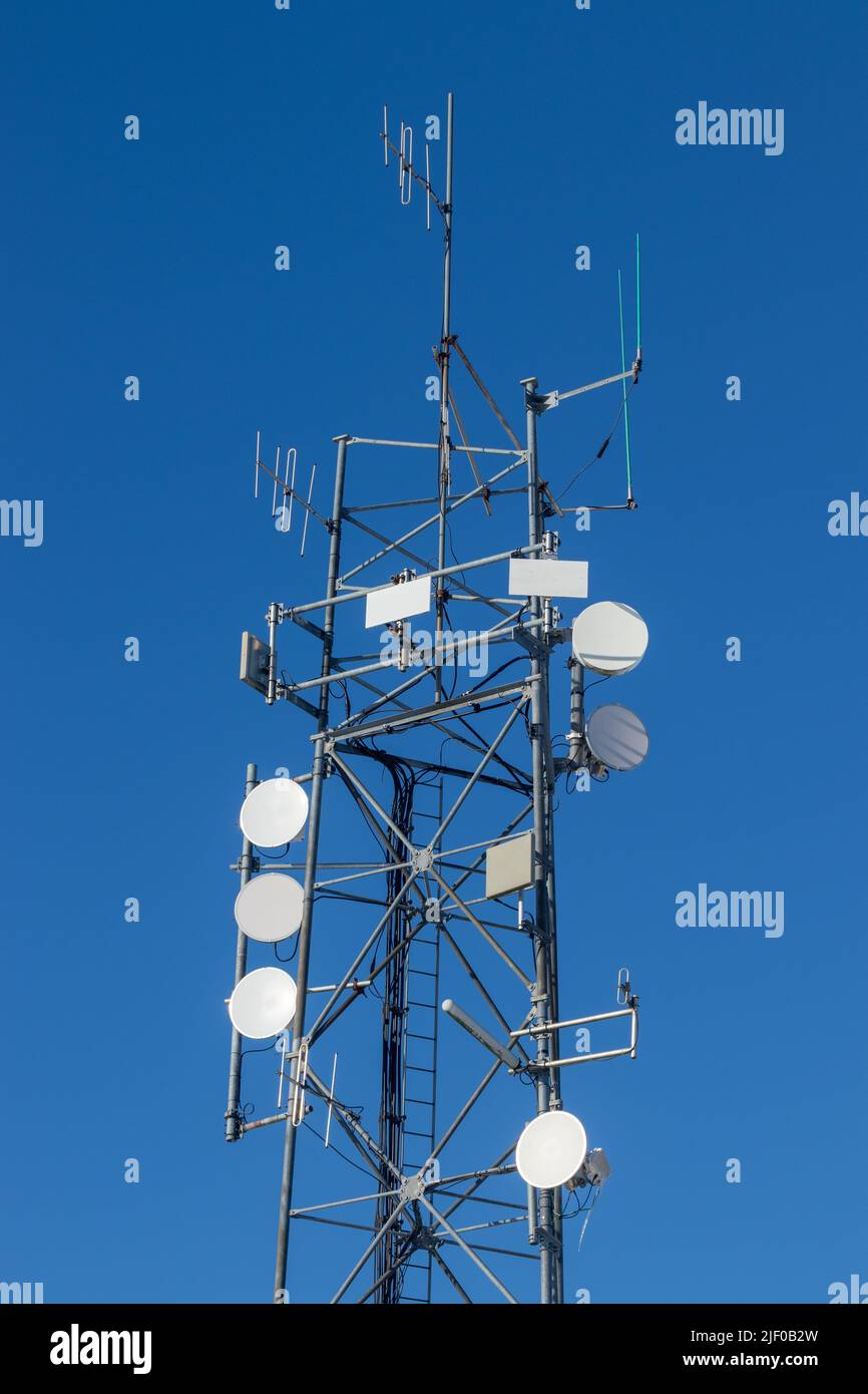 Una torre de comunicaciones contra un cielo azul Foto de stock