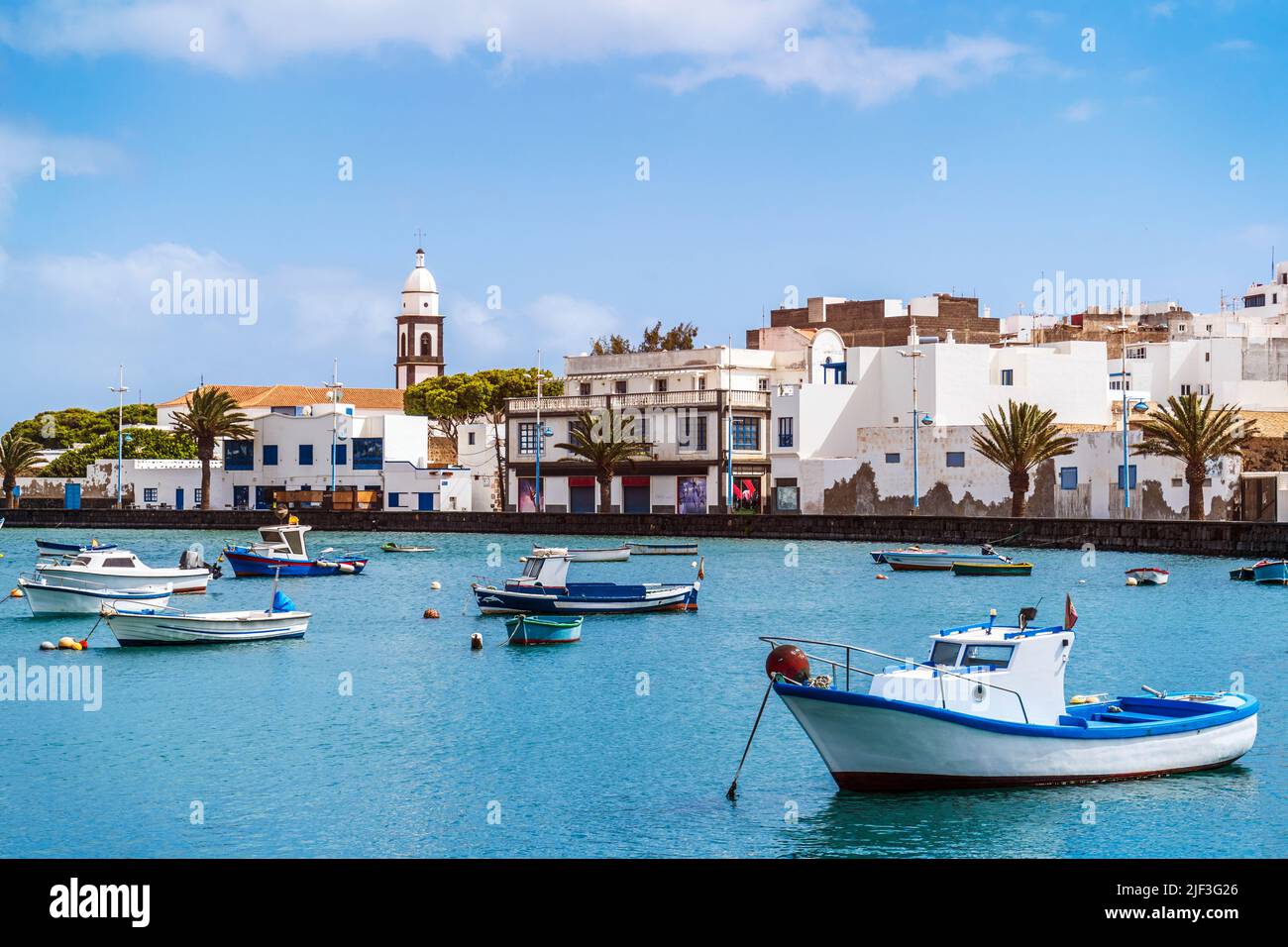 Hermoso muelle con arquitectura histórica y barcos en aguas azules en Arrecife, capital de Lanzarote, Islas Canarias, España Foto de stock
