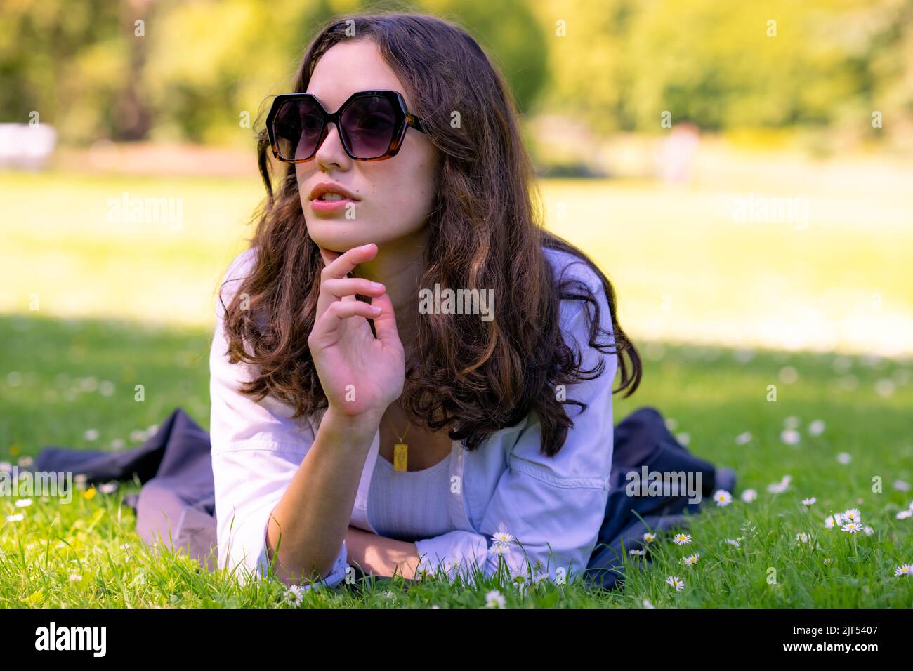 Retrato de una joven puesta en prona sobre hierba en un parque Foto de stock