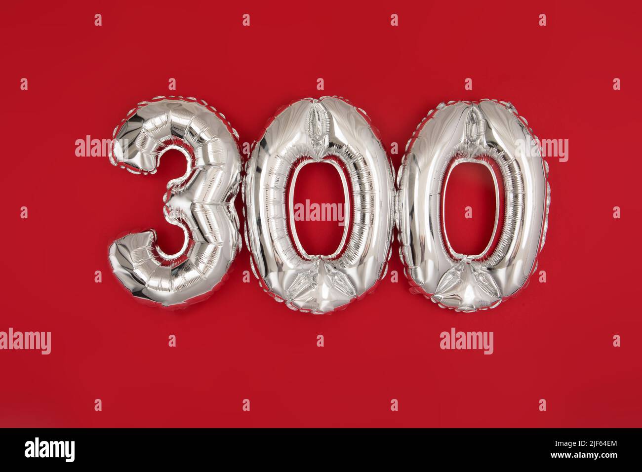 Globo plateado con el número 300 sobre fondo rojo Foto de stock