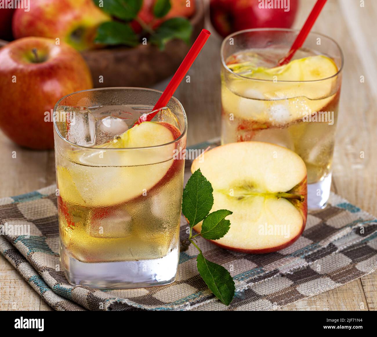 Primer plano de vaso frío de zumo de manzana con manzanas en rodajas y manzanas de fondo Foto de stock