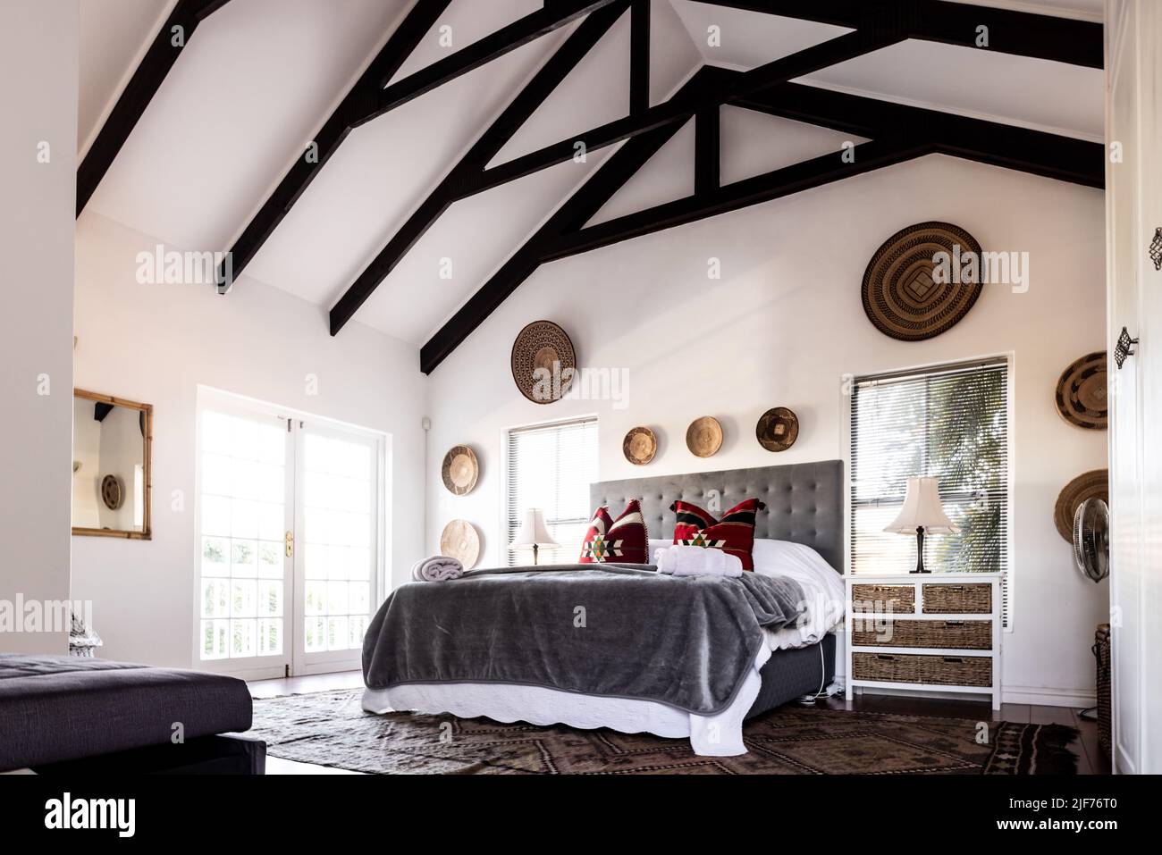 Una cama limpia y vacía con mantas y almohadas bajo el techo de la mansarda en el dormitorio moderno, espacio para copiar Foto de stock
