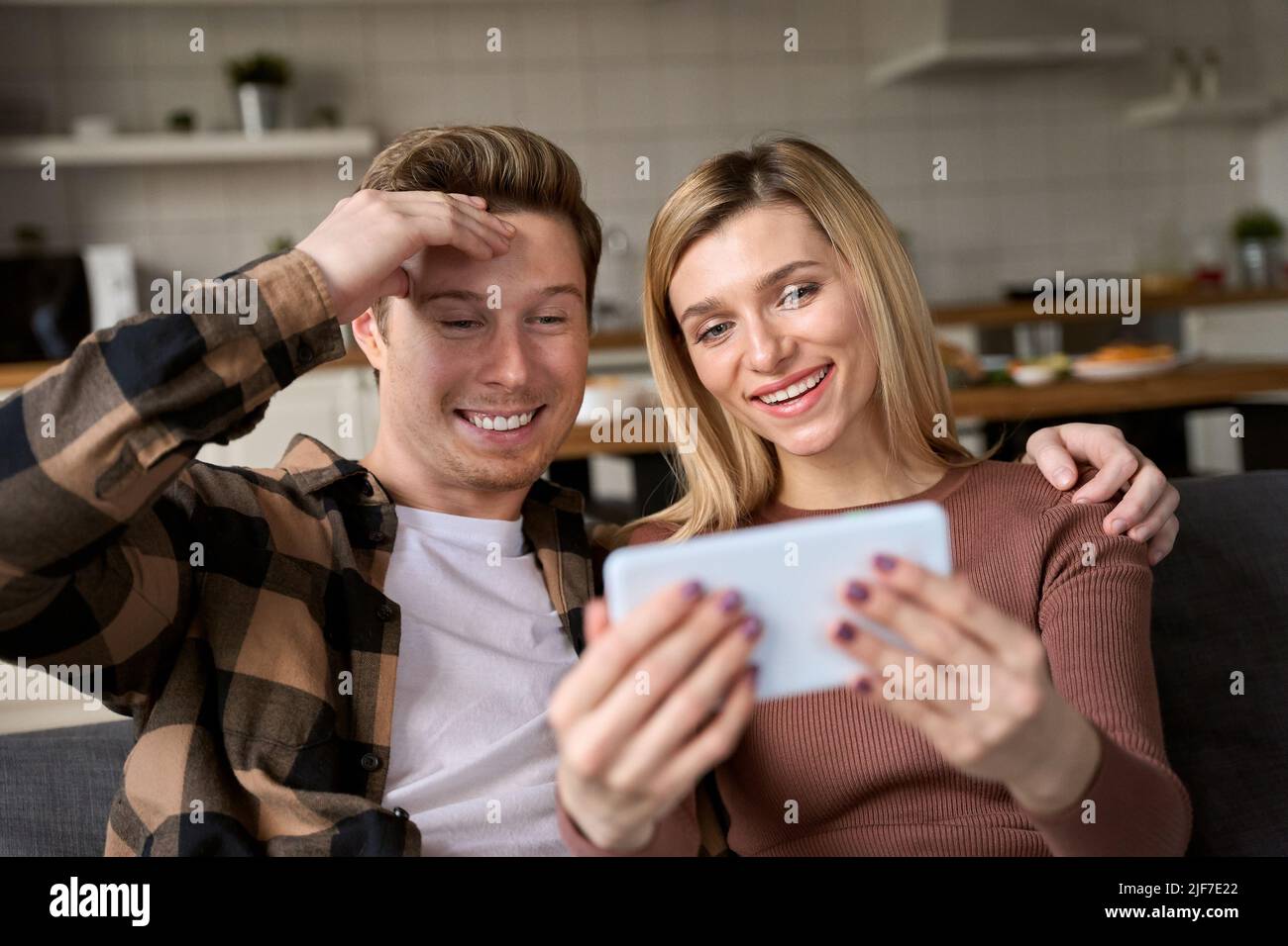 Una pareja feliz usando el smartphone en casa jugando a un juego o haciendo un chat de vídeo. Foto de stock