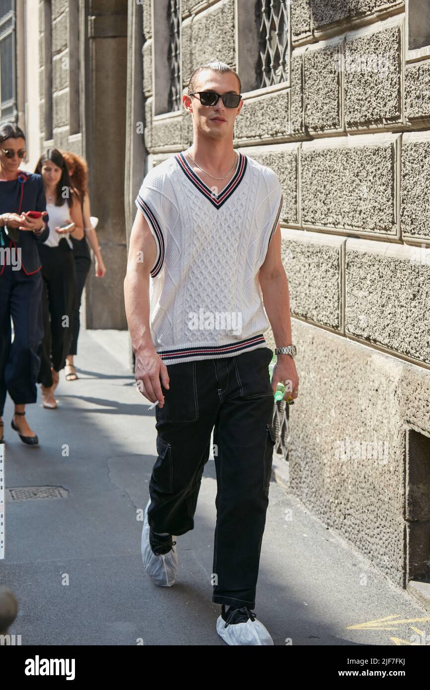 MILÁN, ITALIA - 20 DE JUNIO de 2022: Hombre con suéter blanco y pantalones negros antes del desfile Giorgio Armani, Milán Fashion Week Street Foto de stock