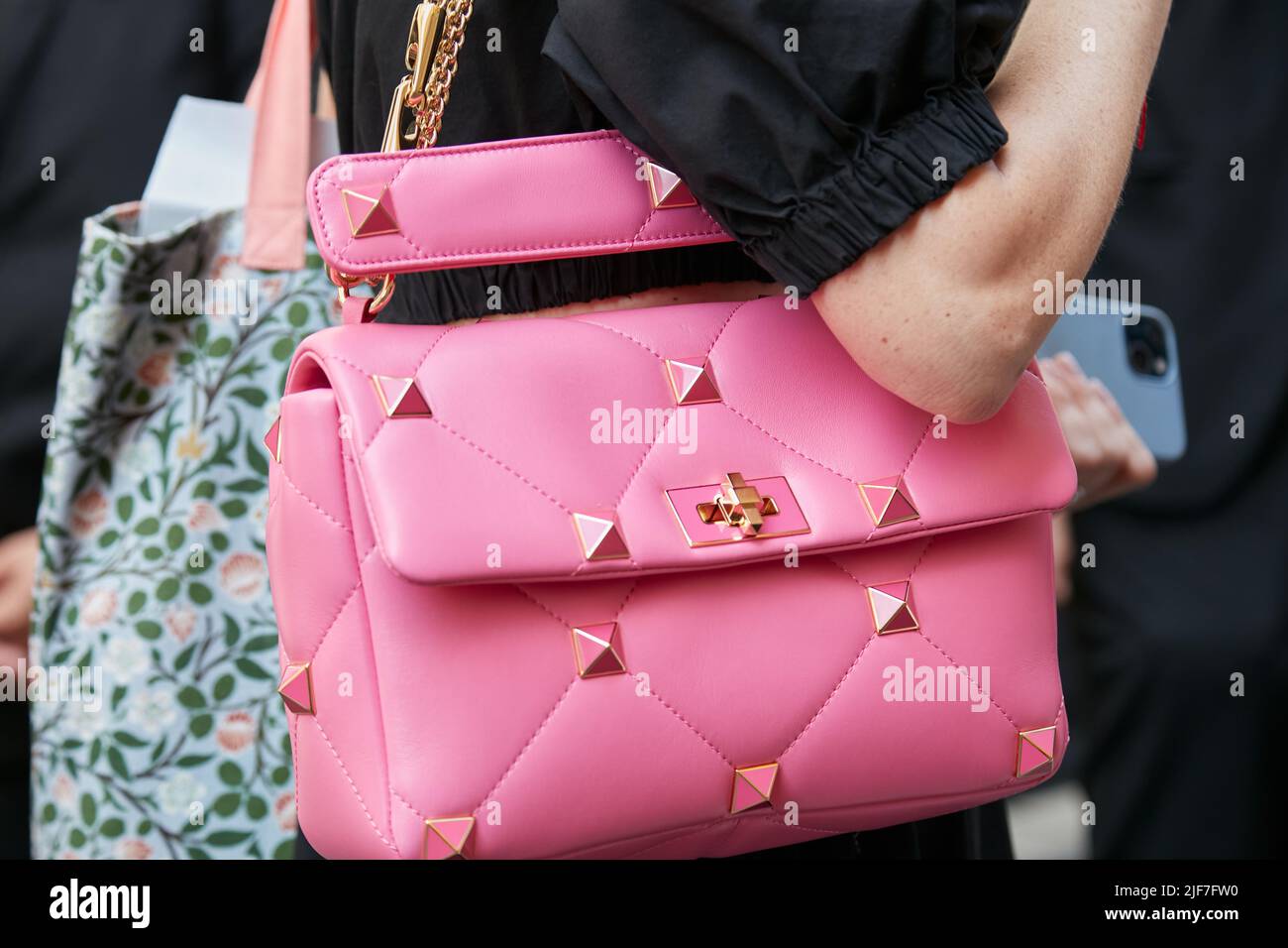 MILÁN, ITALIA - 20 DE JUNIO de 2022: Mujer con bolsa de cuero rosa con tacos de oro y rosa antes de Giorgio Armani desfile, Milán Fashion Week calle sty Foto de stock