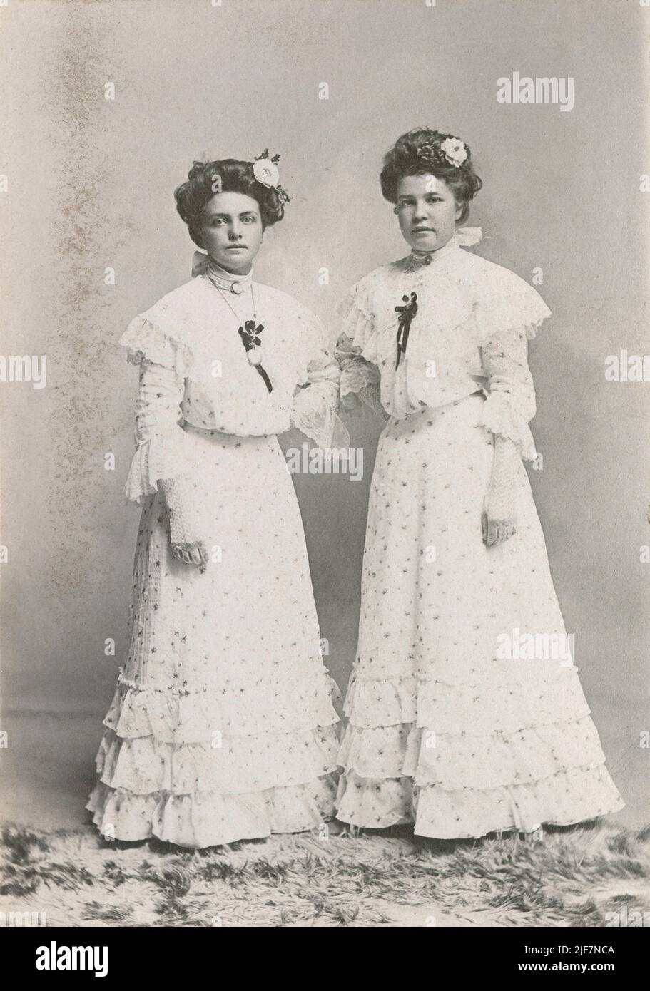 Antique circa 1880 Fotografía de dos hermanas o damas de honor en Cadillac, Michigan vestidas con los mejores vestidos florales blancos. FUENTE: TARJETA DE GABINETE ORIGINAL Foto de stock