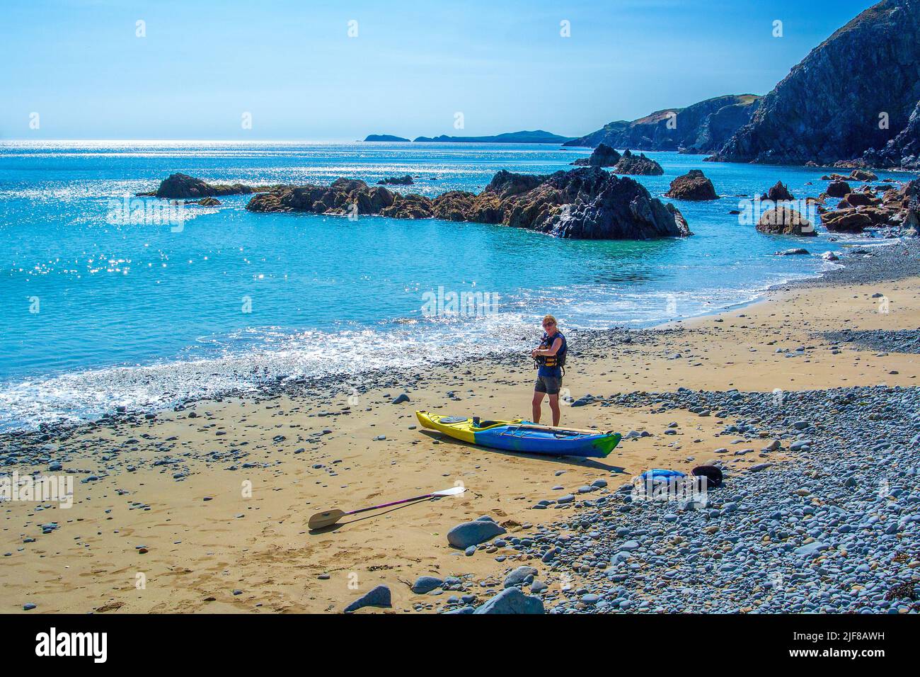 Kayak de mar femenino en la playa cerca de Solva en la costa de Pembrokeshire en Gales Foto de stock