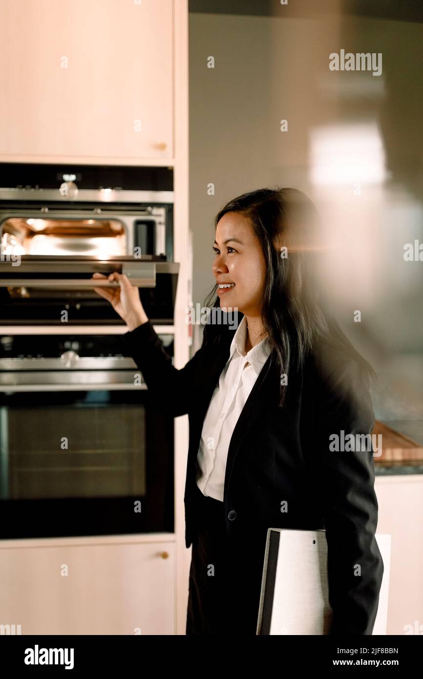 Agente inmobiliario abriendo microondas en la cocina en su nuevo hogar Foto de stock