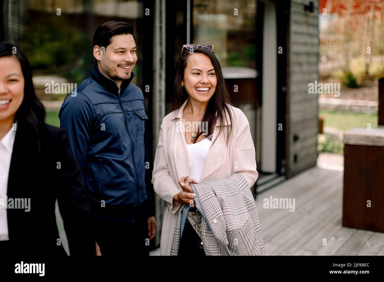 Una pareja feliz de pie junto a una vendedora fuera de la casa Foto de stock