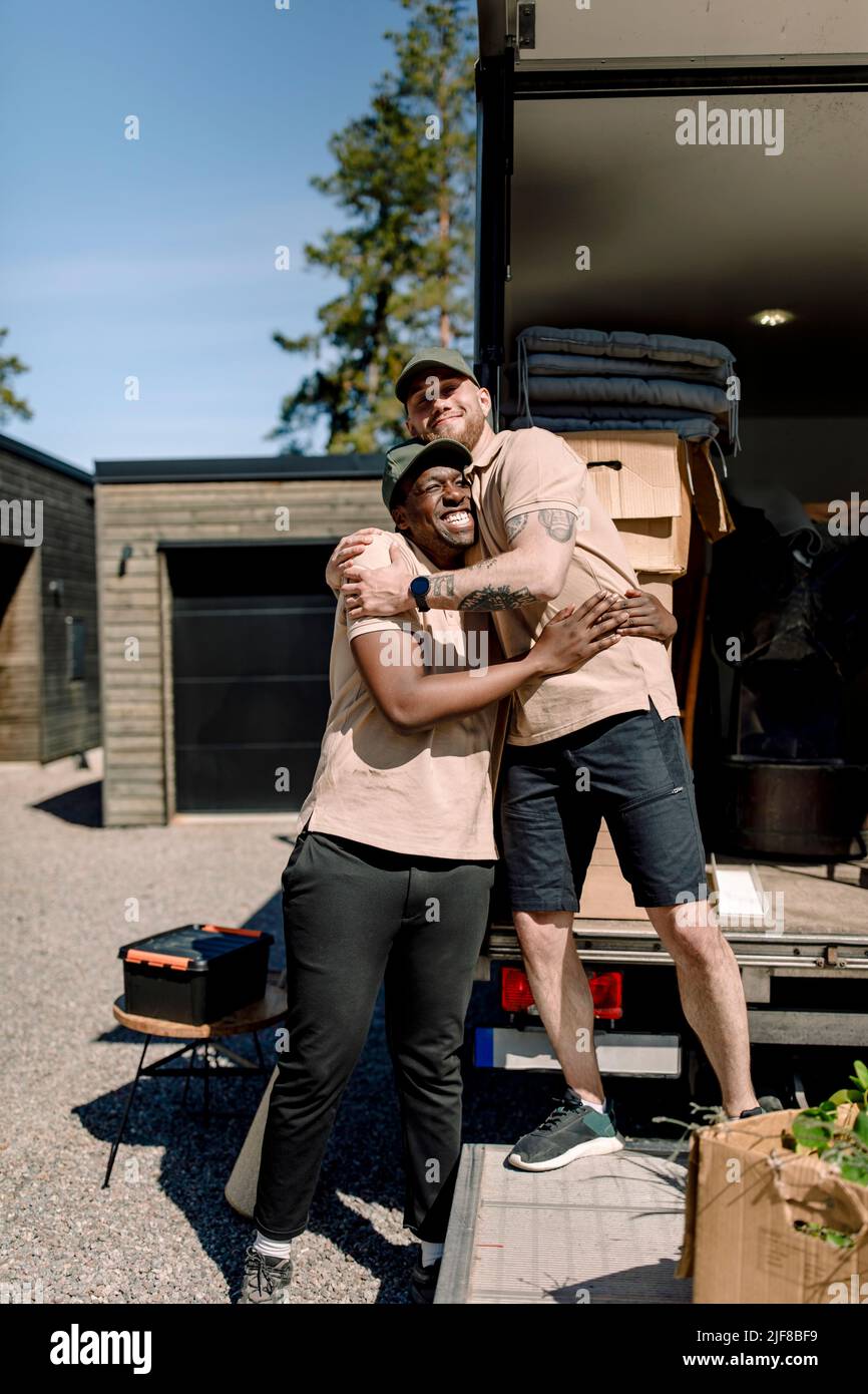 Feliz entrega hombres abrazando mientras que está fuera del camión Foto de stock