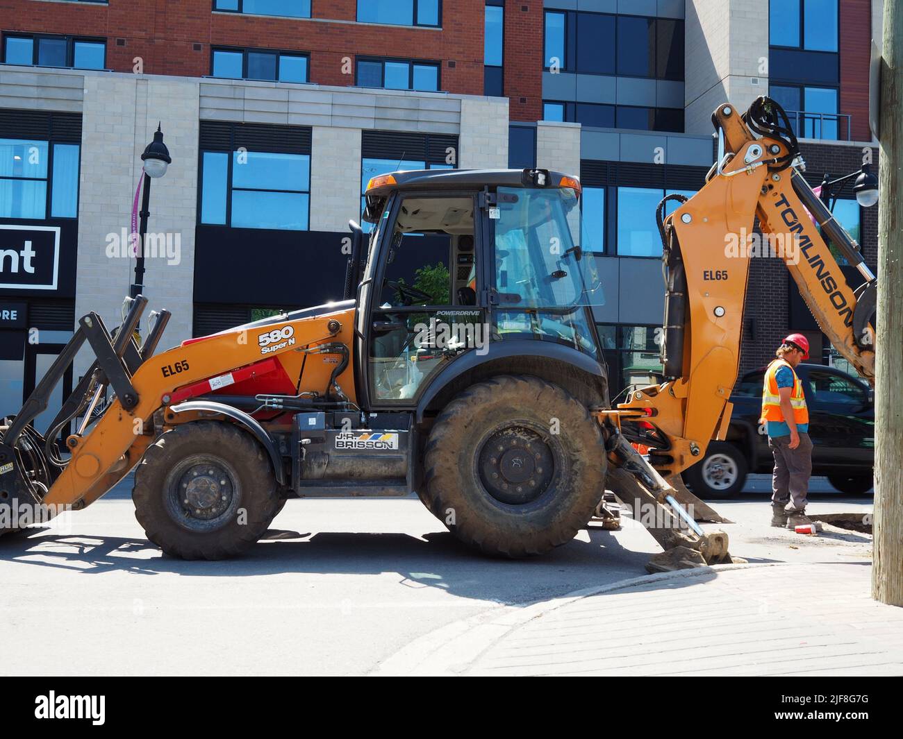 Equipo de construcción en Bank Street. Bulldozer naranja con retroexcavadora y tripulación. Ottawa, Ontario, Canadá. Foto de stock