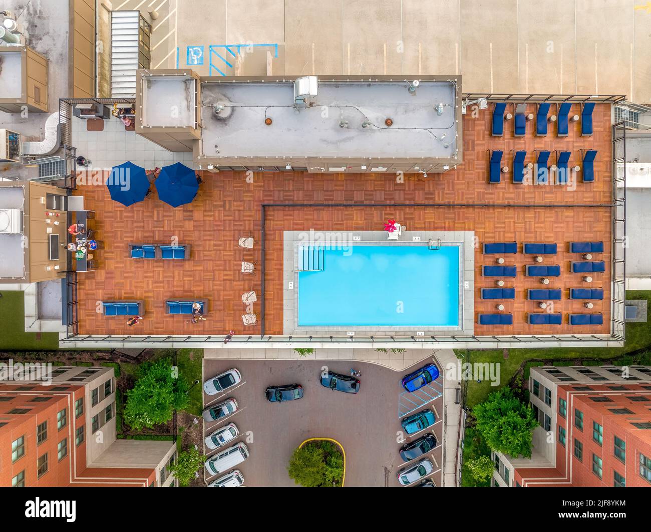 Vista aérea de la piscina en la azotea con filas de tumbonas azules, parrilla, bar en la parte superior de un lujoso edificio residencial en el centro de la costa este en los Estados Unidos Foto de stock
