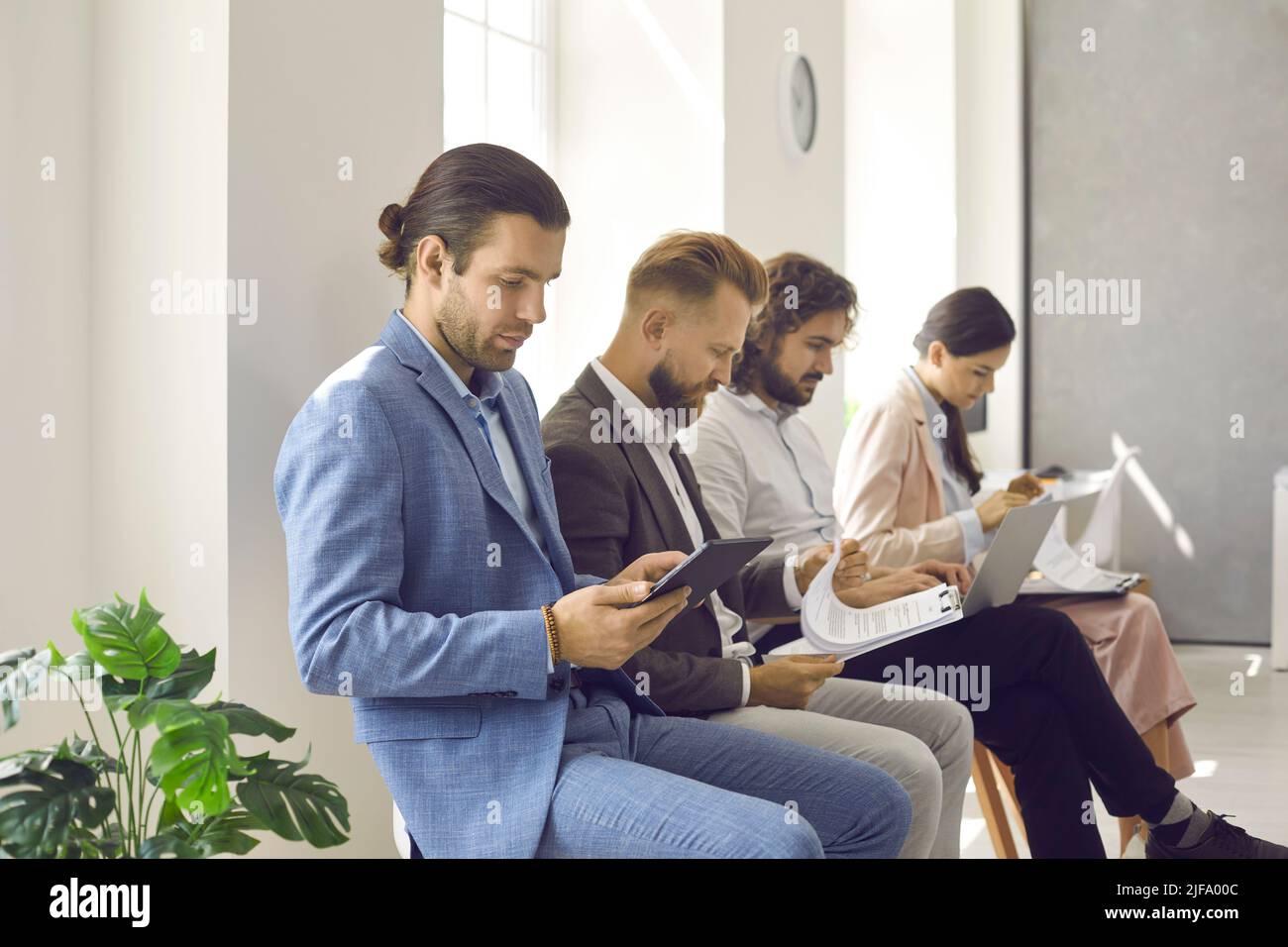 Grupo de gente ocupada sentada en la fila en la oficina y esperando una cita de negocios Foto de stock