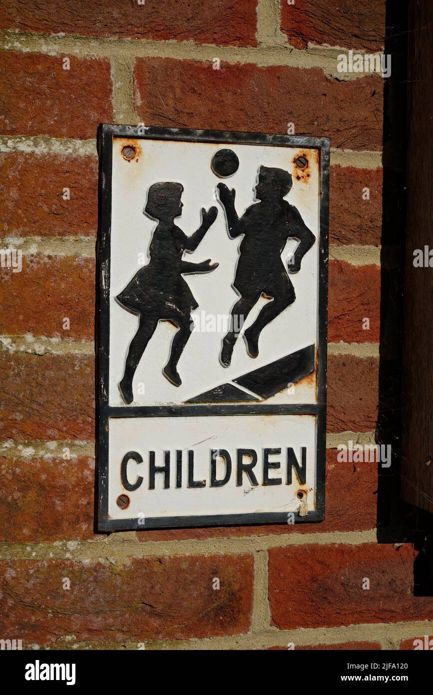 Un antiguo cartel de 'niños' junto a una escuela del Reino Unido. Una antigua señal de seguridad para alertar a los usuarios de la carretera de que una escuela está aquí. Foto de stock