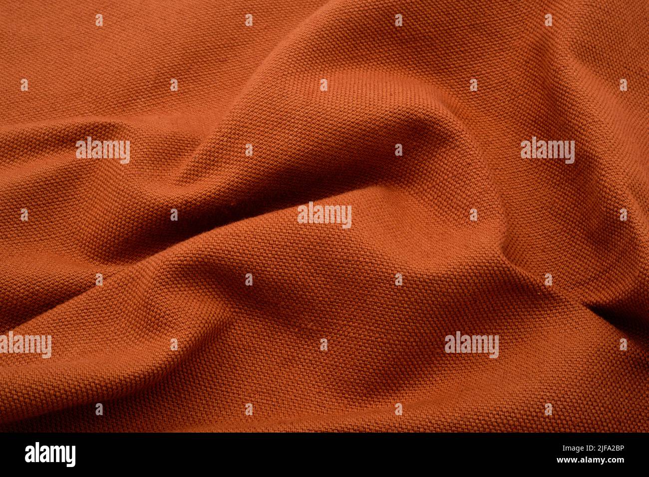 Fondo de tela texturizada. Un tejido fruncido de color naranja terroso. Foto de stock
